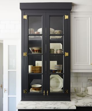 A navy kitchen cabinet with glass fronted doors