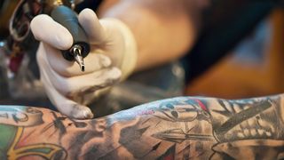 A close up of a tattoo artist drawing a tattoo