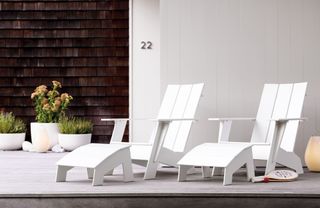 A pair of white Adirondack chairs on a modern front porch
