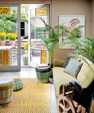 colorful living room with yellow leaded glass doors, green sofa, yellow rug and colorful wicker stools