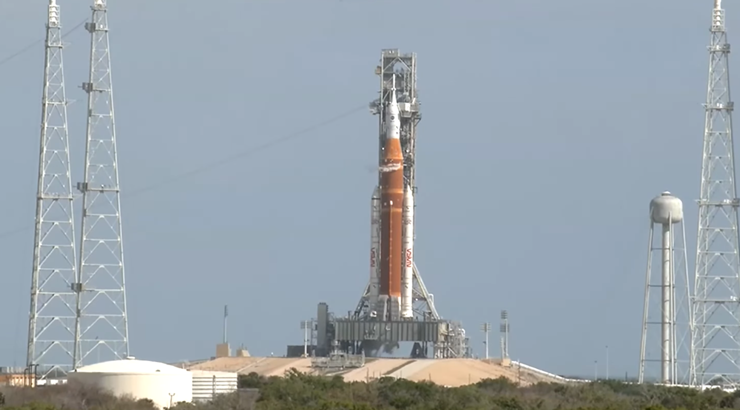 The Artemis II rocket, with small streams of steam from vented fuel on the top and bottom sections of the rocket.