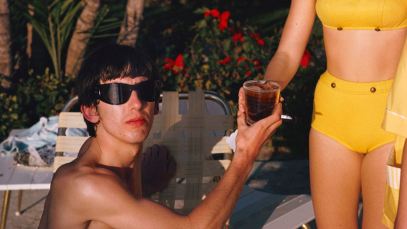 man in sunglasses with drink poolside