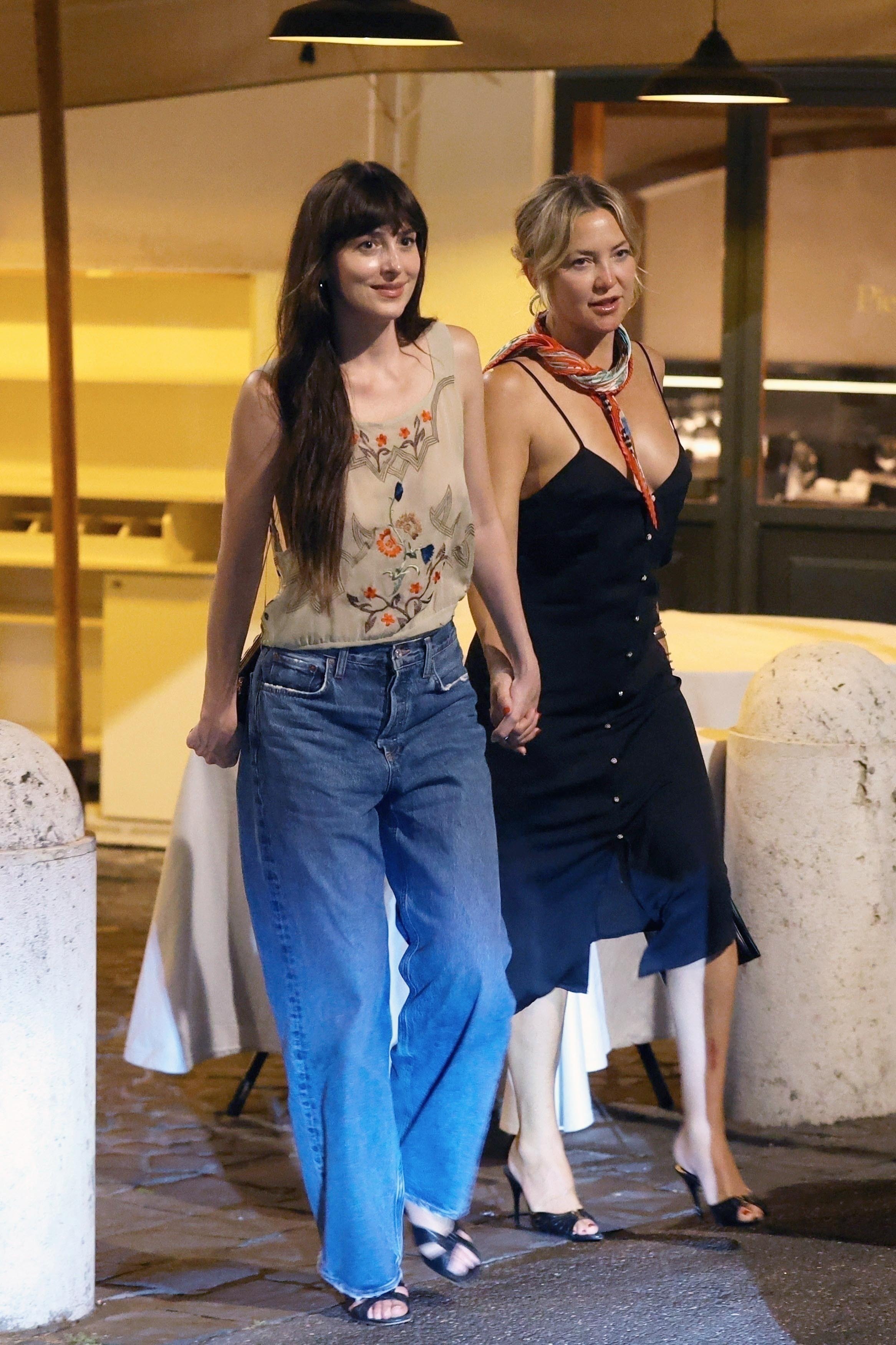 Dakota Johnson walked outside with Kate Hudson. She wore a vintage-style top with loose jeans and black high heeled sandals.