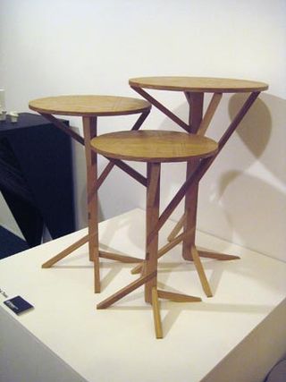 Three wooden side tables in different heights, displayed on a white platform