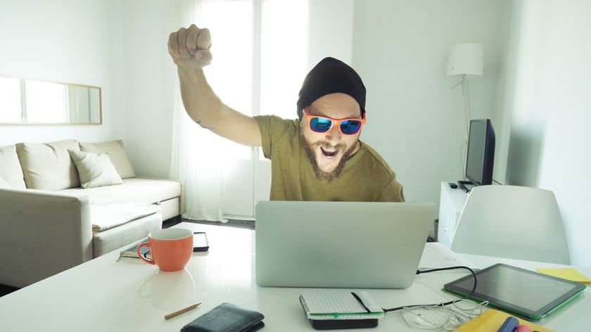 Man celebrates while looking at laptop.