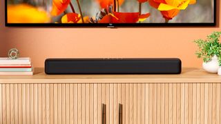 Amazon Fire TV Soundbar on a wooden table under a TV