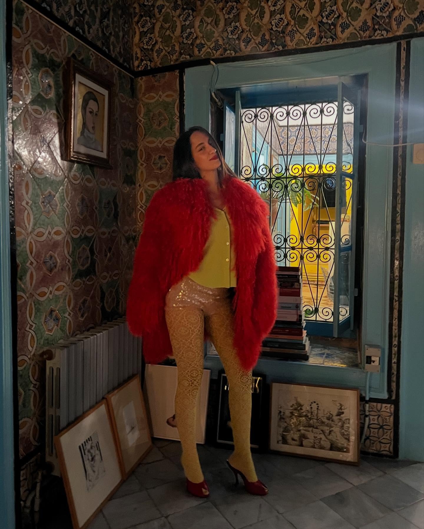 An image of Emna Sellimi wearing a fur coat with patterned tights and sequined microshorts.