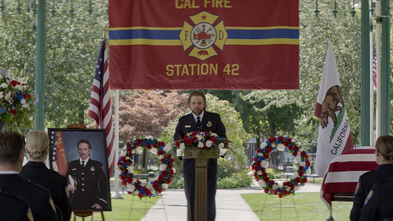 Bode speaking at Vince's funeral. A photo of Vince is sitting to his left.