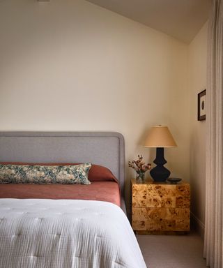 bedroom with neutral walls and gray bedhead with floral pillow