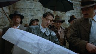 Adrien Brody looking over a blueprint in The Brutalist