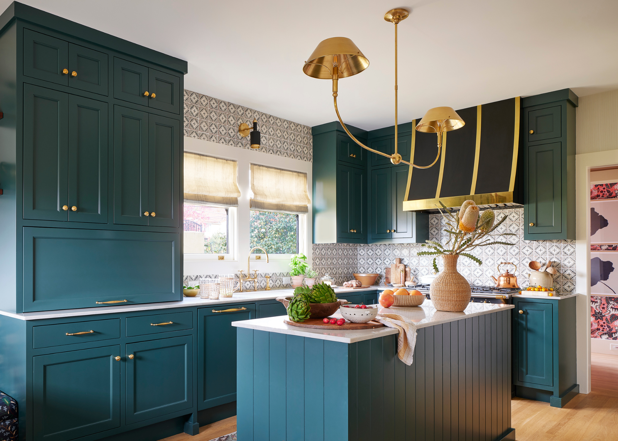 A teal blue modern traditional kitchen brought to life with playful color styling on the island and statement extractor hood and light above the island