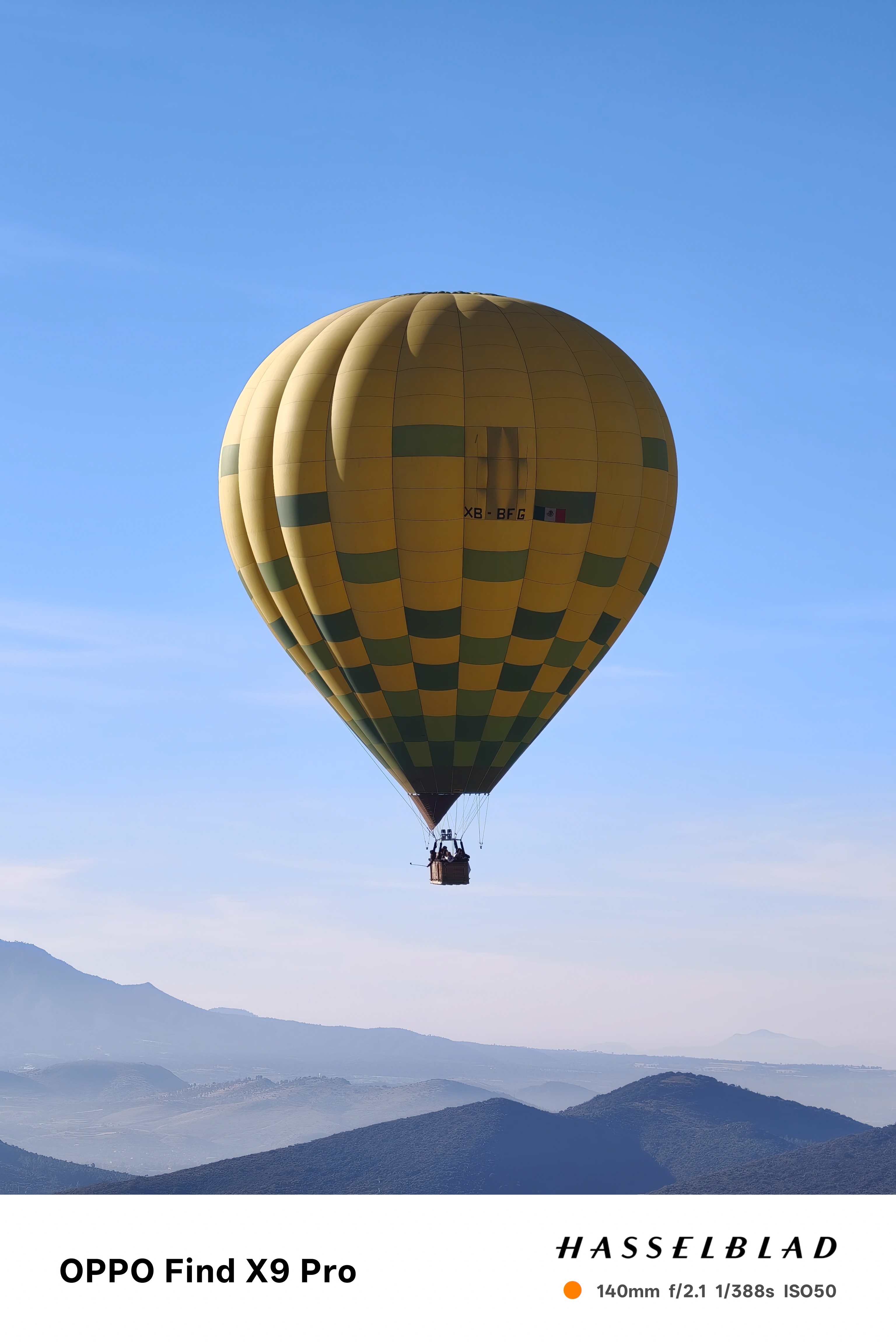 A yellow hot air balloon in front of a clear  sky