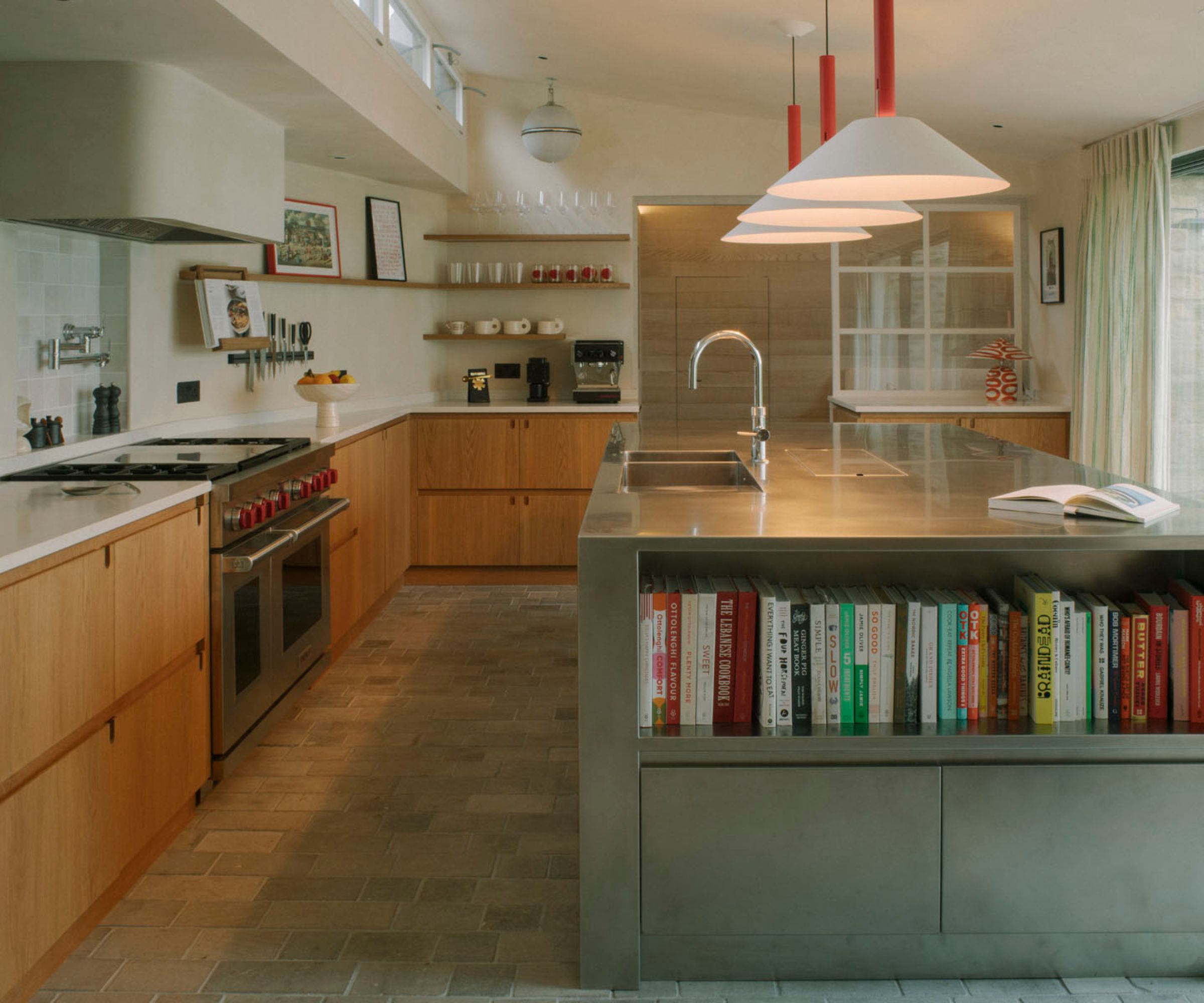 A wooden kitchen with warm white walls and a stainless steel island