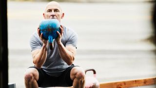 Man performs goblet squat with a kettlebell