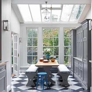 grey kitchen with dining table, glass ceiling and doors and checkered tiles