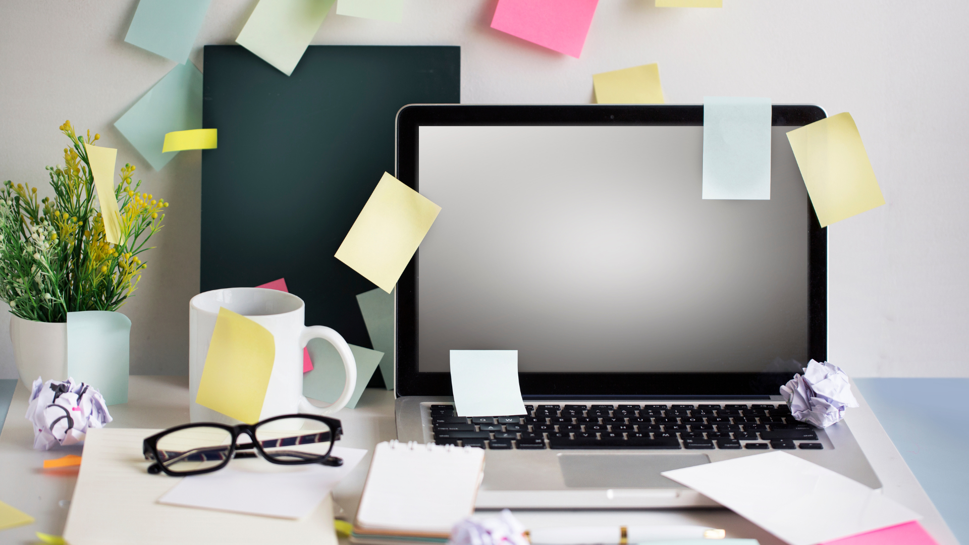 A computer desk with post it notes scattered around