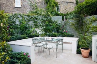 garden privacy ideas: high fence painted green behind a seating area