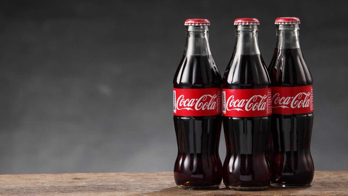 Three Coca-Cola bottles on a wooden surface