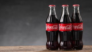 Three Coca-Cola bottles on a wooden surface