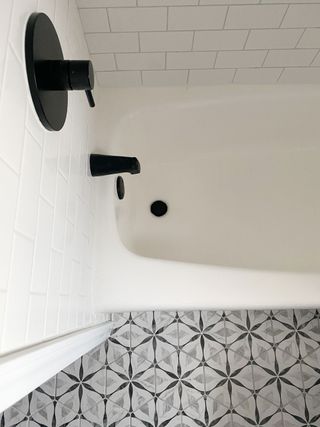 Refinished bathtub with black fittings and patterned floor tiles