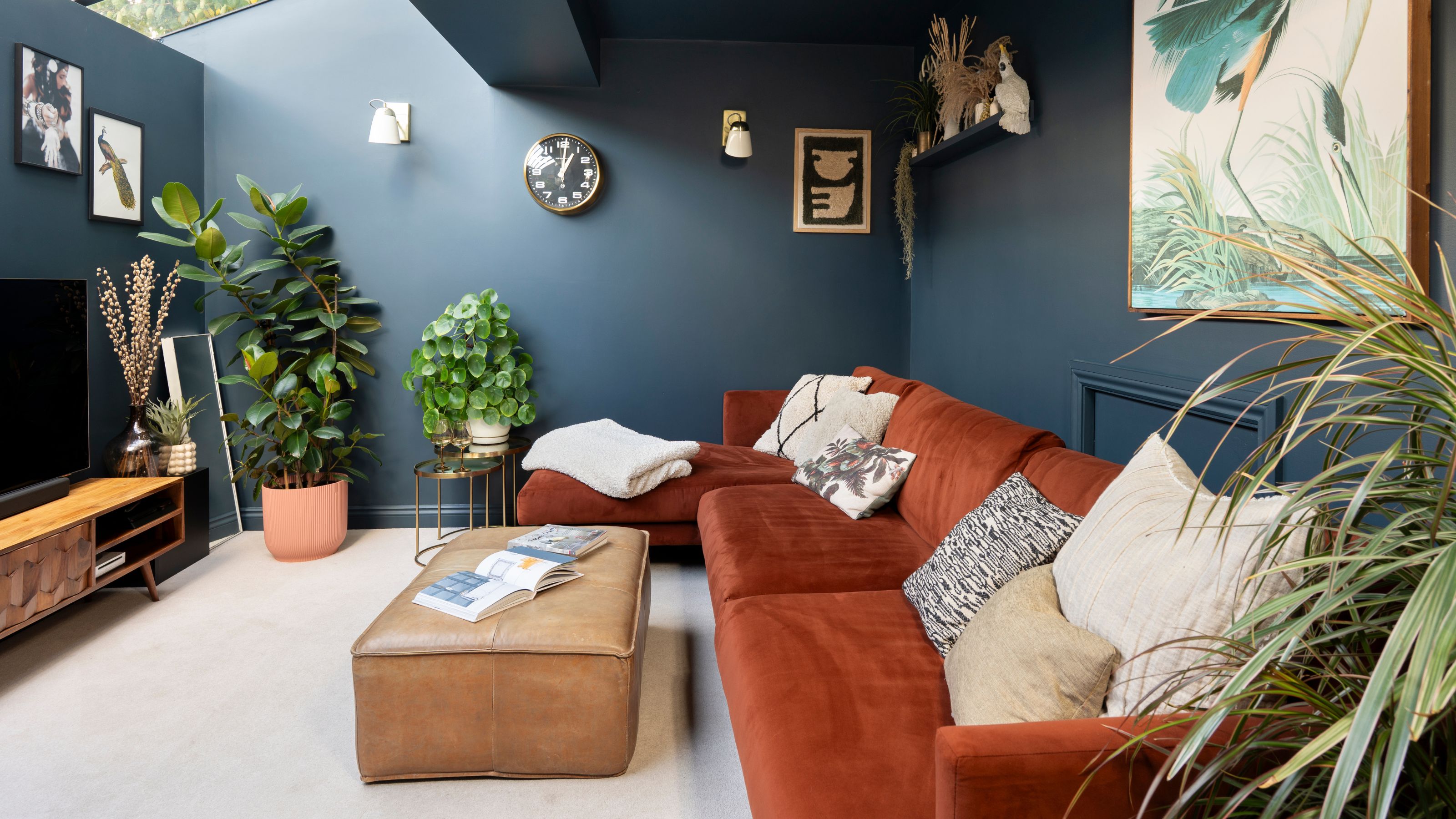 Blue living room with an orange sofa and a leather footstool, on cream carpets