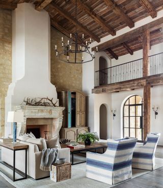 living room with blue and white armchairs cream sofa and white chimney breast and exposed wooden rafters and stone walls