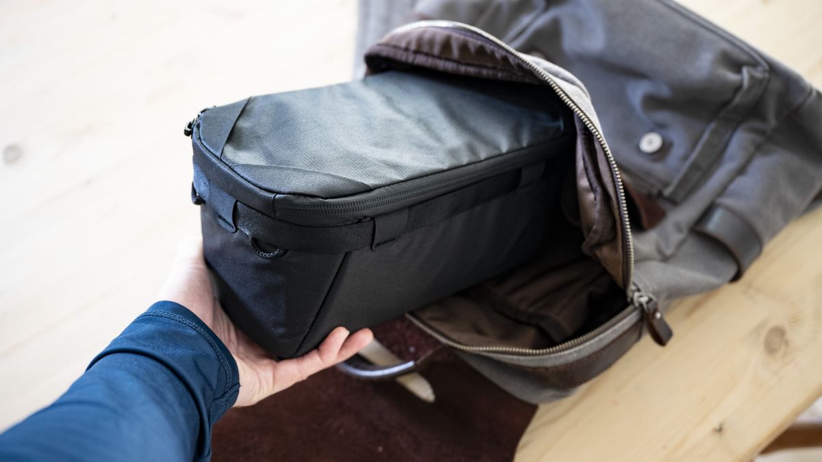 Peak Design Camera Cube being taken out of a regular bag on wooden table outside