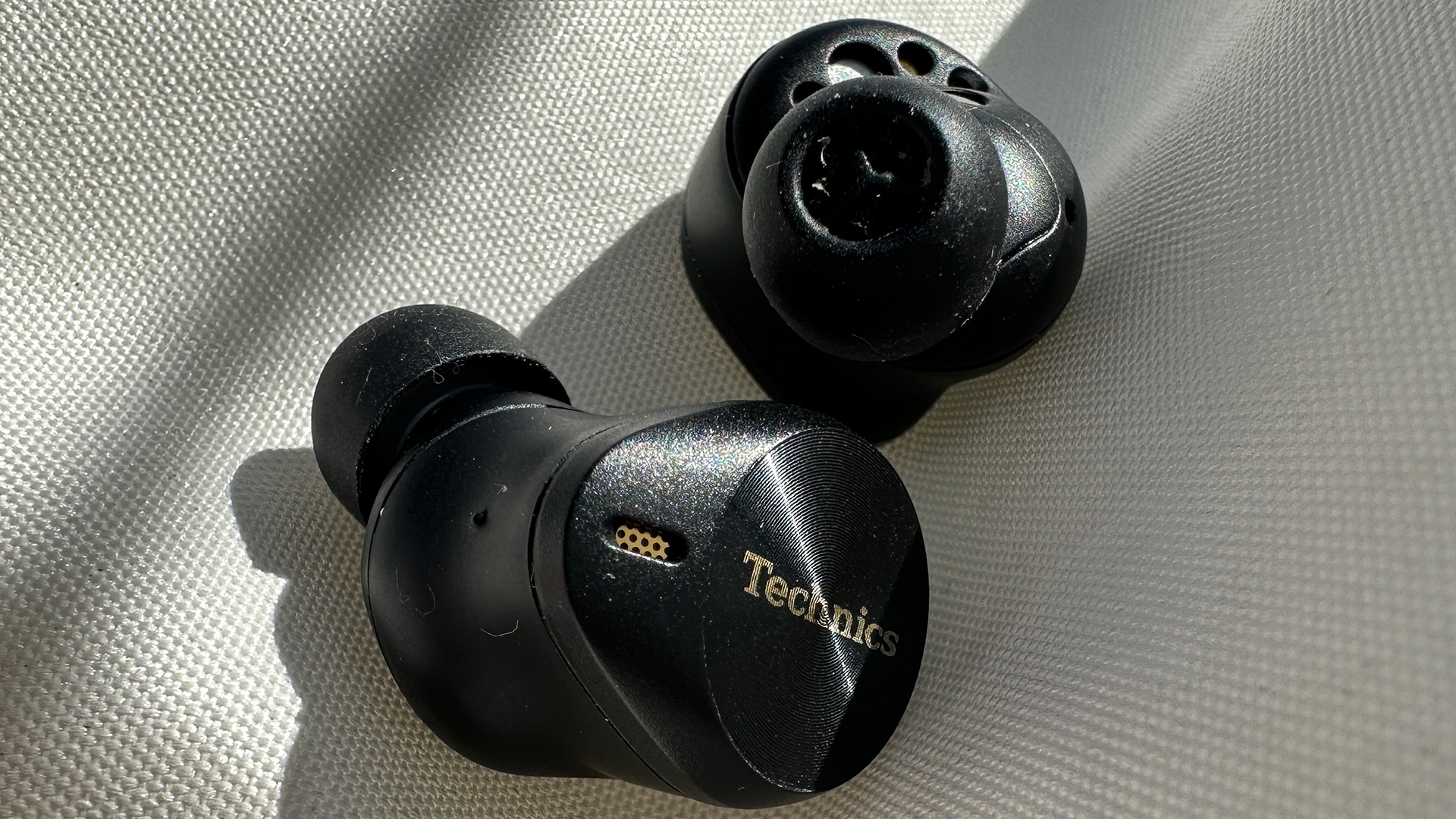 The Technics EAHAZ80 earbuds one facing up and the other down