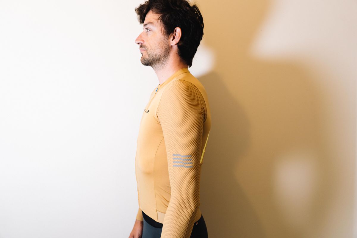 A white man in a tan jersey against a white wall