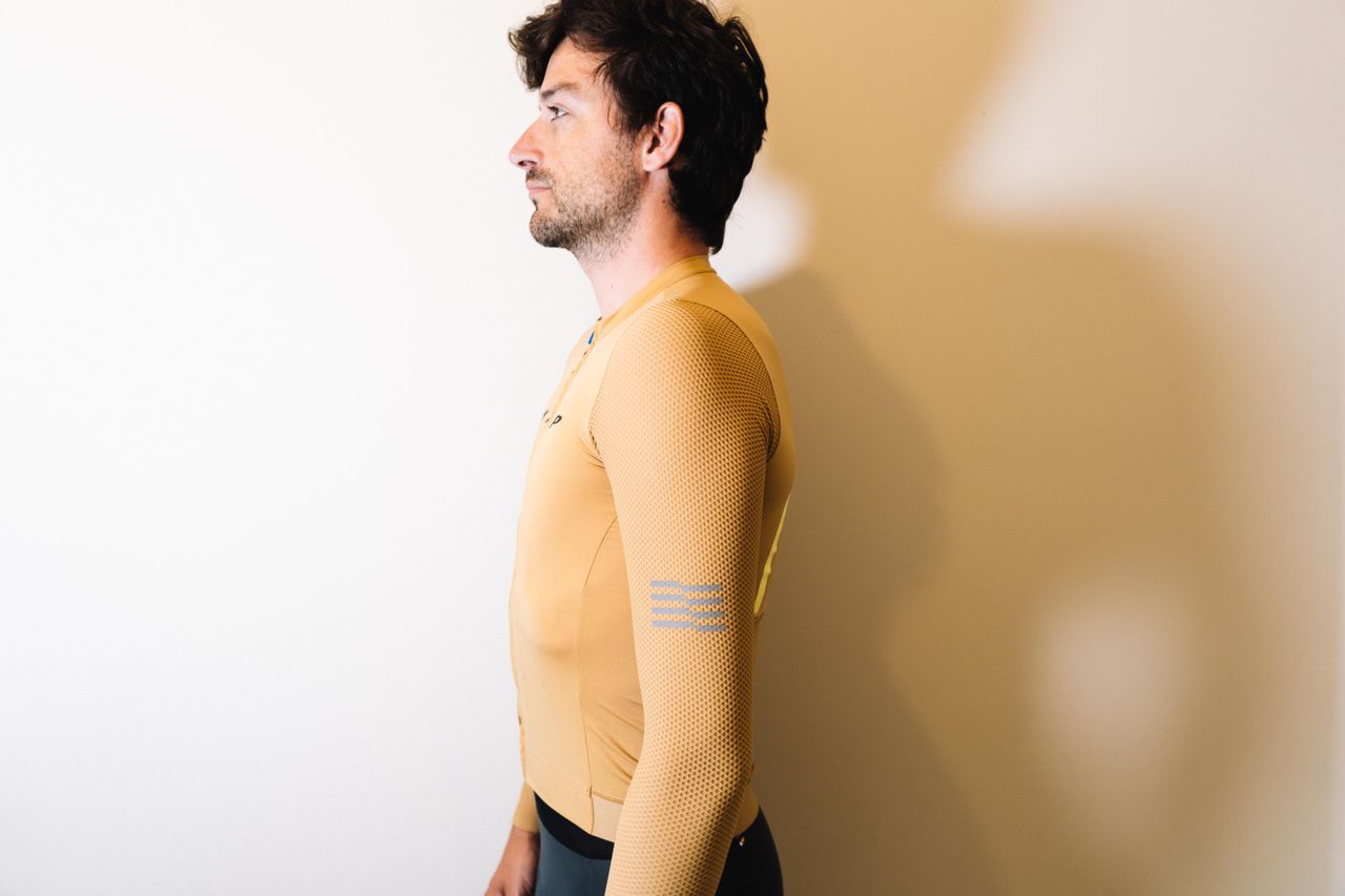 A white man in a tan jersey against a white wall