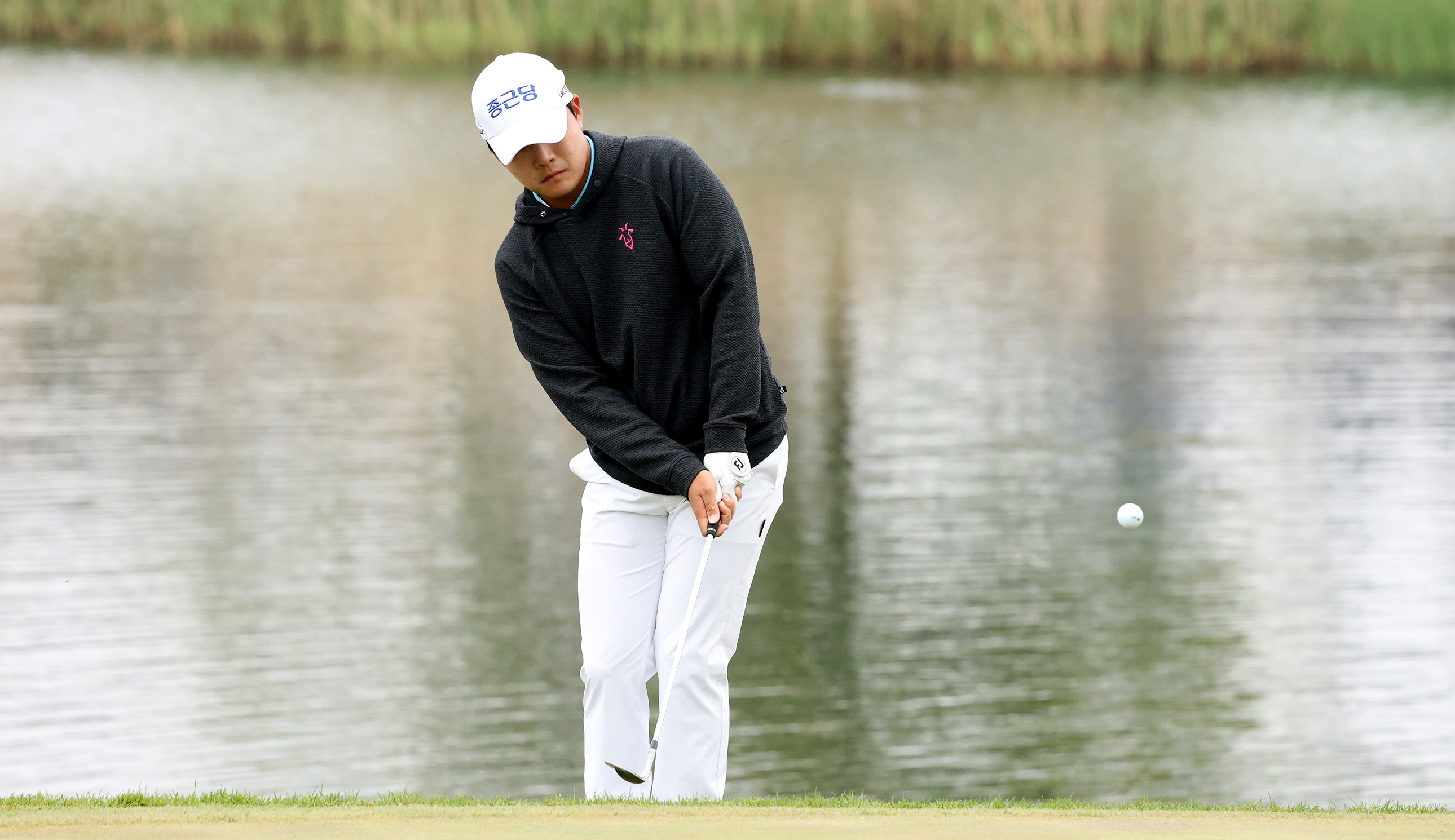 Minkyu Kim hits a chip shot off the edge of the green