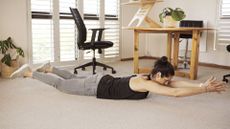 Woman laying face down on a yoga mat doing back exercises
