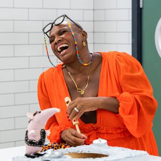 Andi Oliver laughing in a bright orange dress