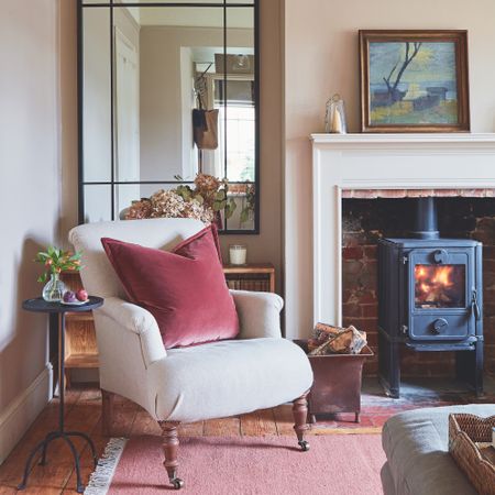 cream chair in cottage living room with woodburning stove and large mirror in alcove