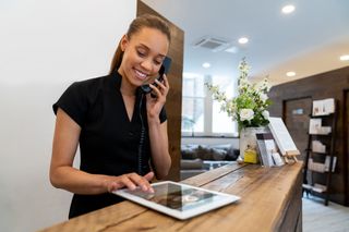Woman spa assitant answering the phone and using a tablet in reception setting