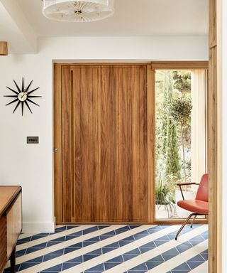 An entryway with a wooden door and blue and white striped tiles