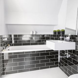 bathroom with grey tiled walls and white washbasin