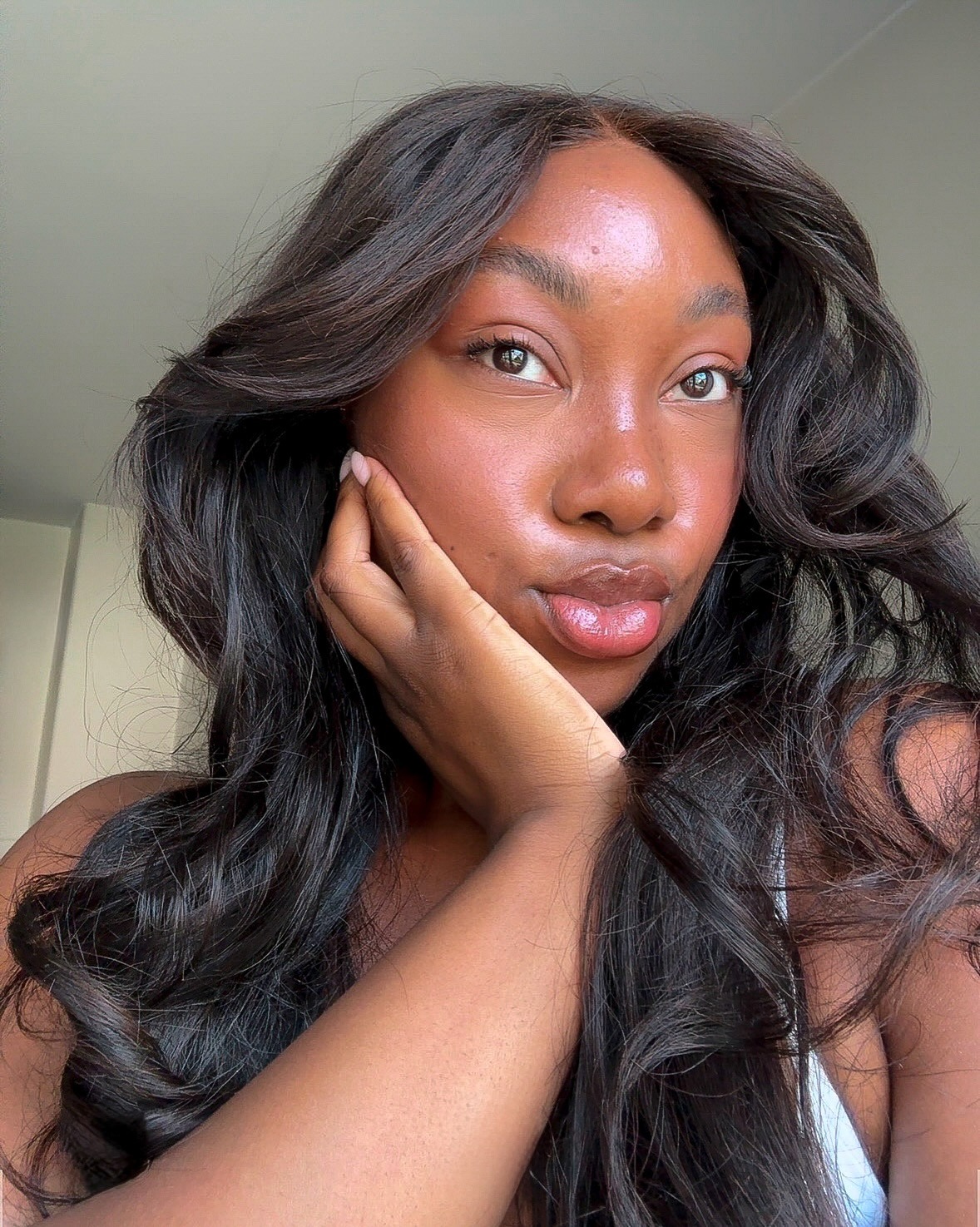 A woman with dark brown, wavy hair taking a selfie