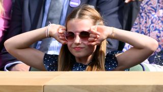 Princess Charlotte of Wales stretches out her arms as she watches the Men's Final at Wimbledon 2024