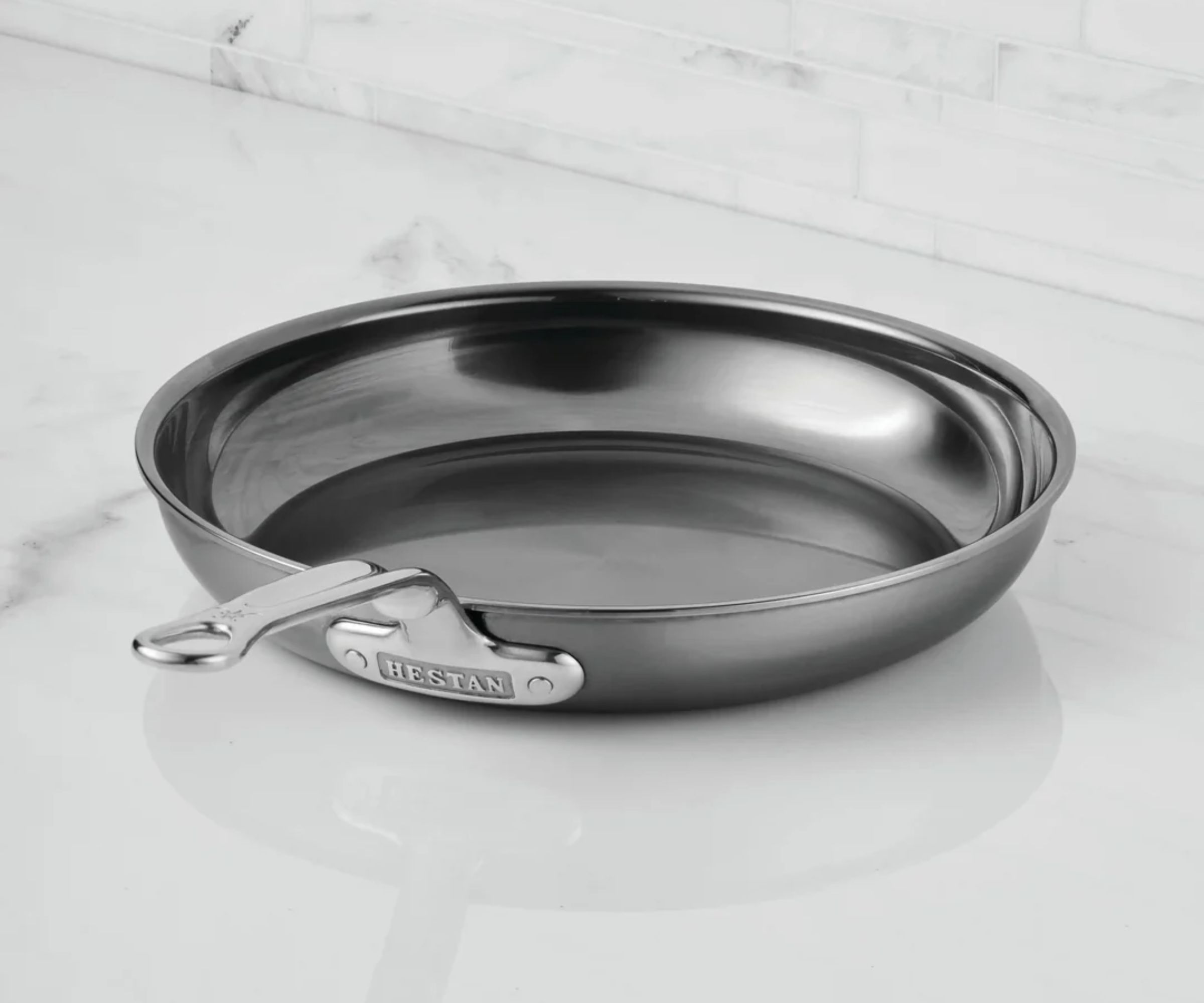 A black frying pan on a white marble kitchen counter