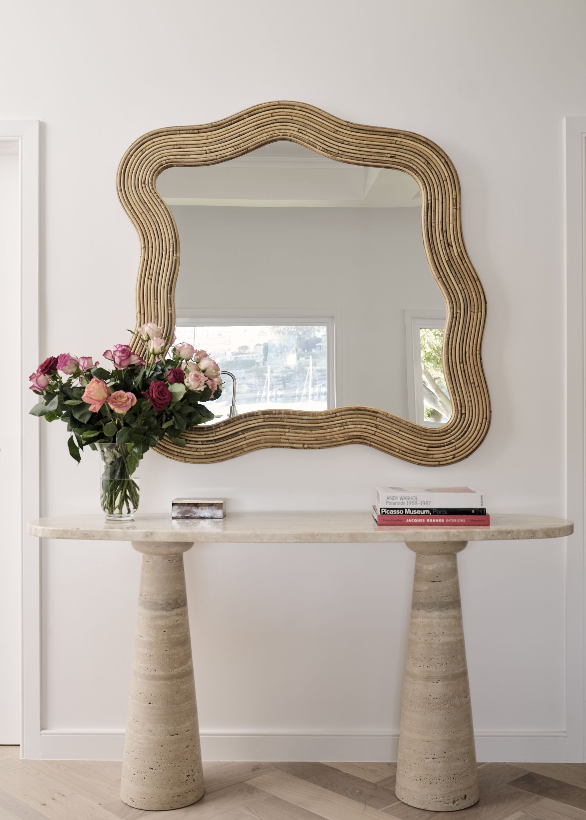 A small living room with an organic shape mirror places above a console