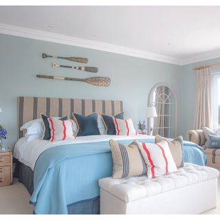 bedroom with teal wall and white end of bed and bedding with cushions and throw