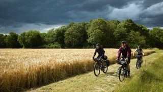 Three cyclists riding along Rebellion Way with moody skies.