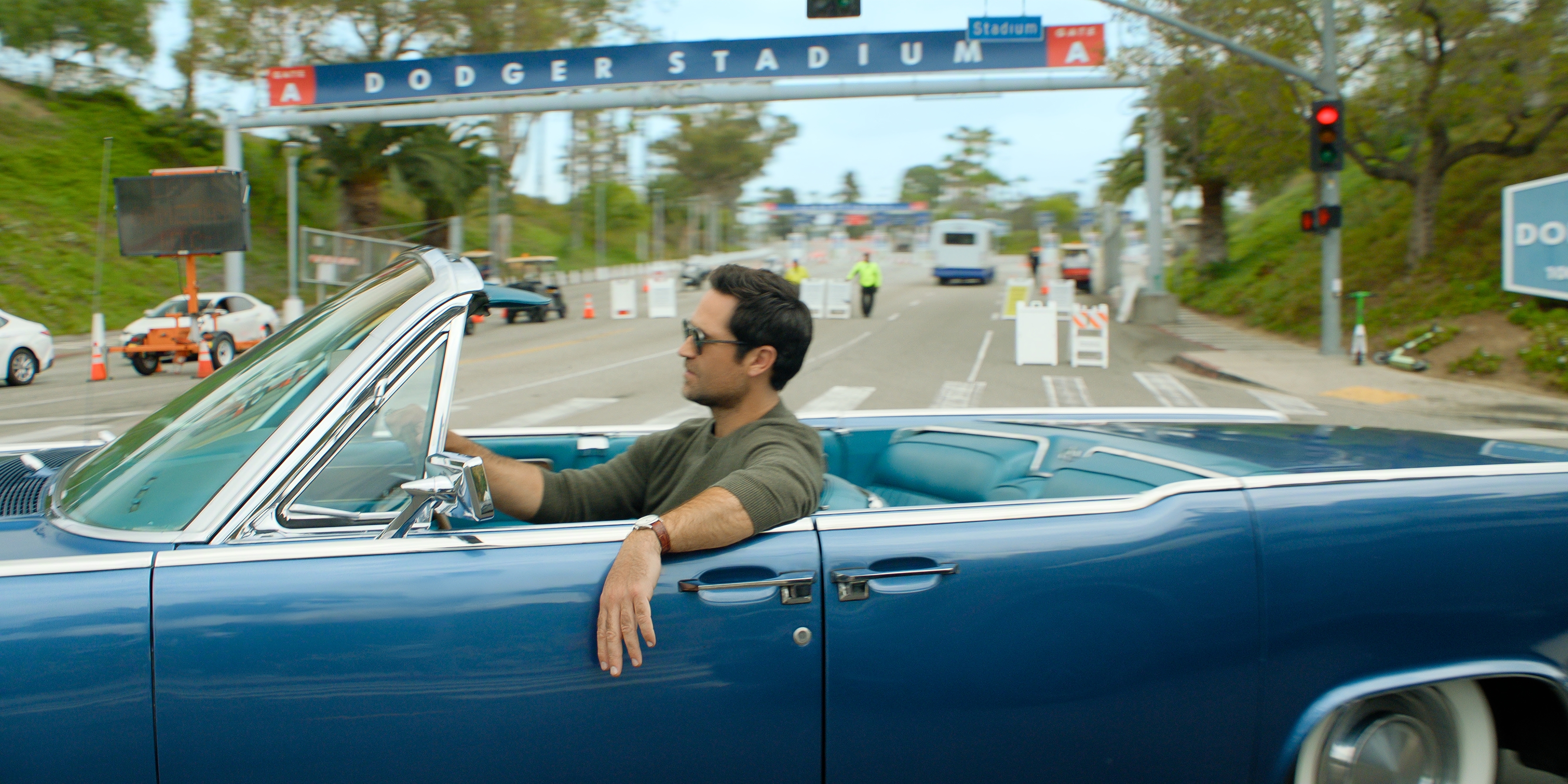 Manuel Garcia-Rulfo as Mickey Haller in the lincoln lawyer season 4 driving a blue car on the highway in traffic