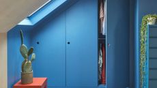 A blue wardrobe with an orange side table and a potted cactus