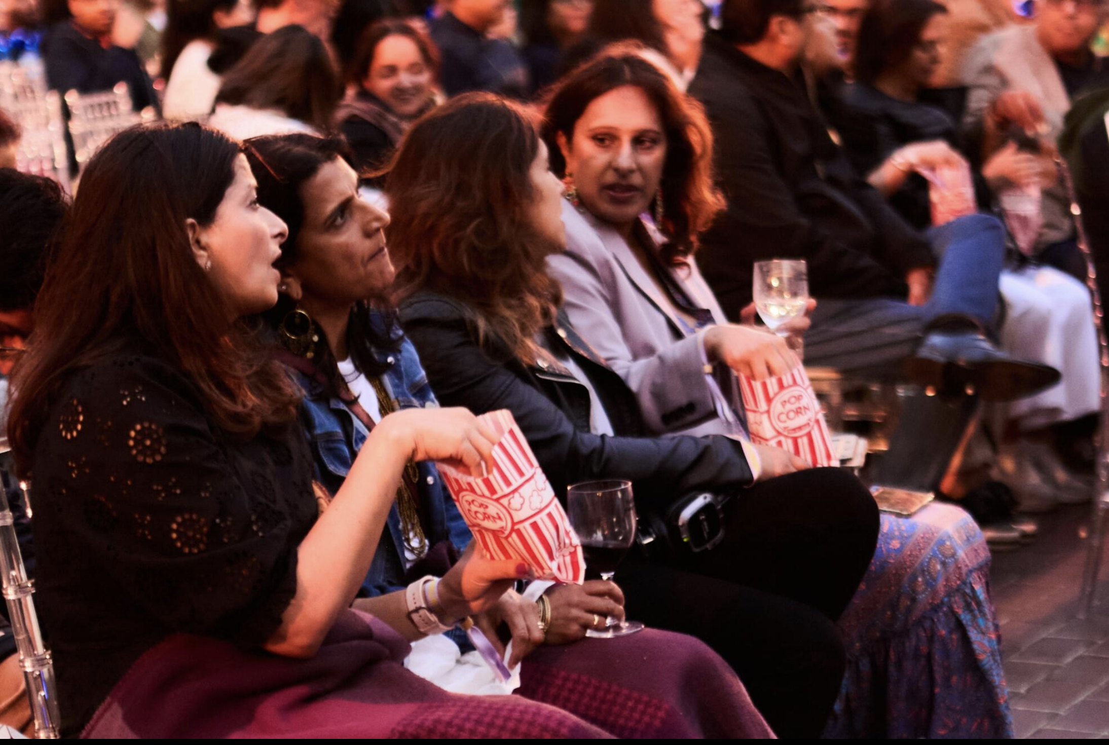 an image of a row of women eating popcorn at the open air cinema