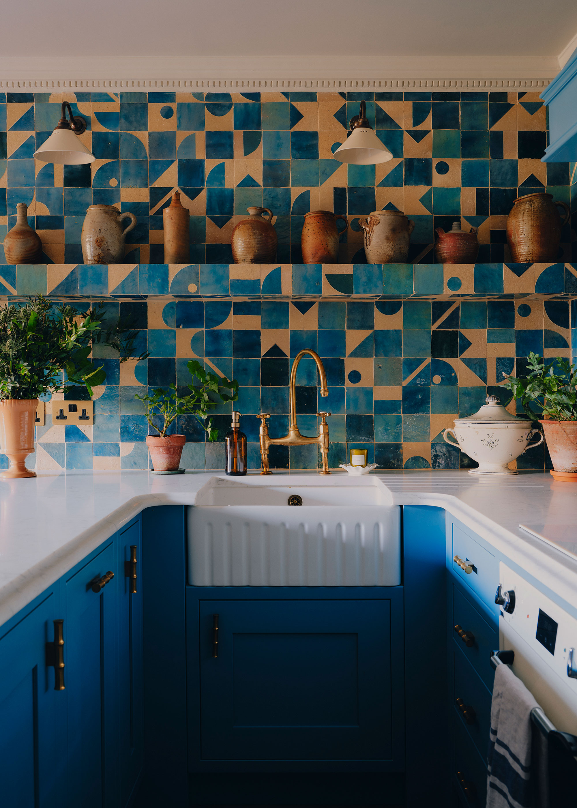 small blue kitchen with fully tiled wall and white countertops