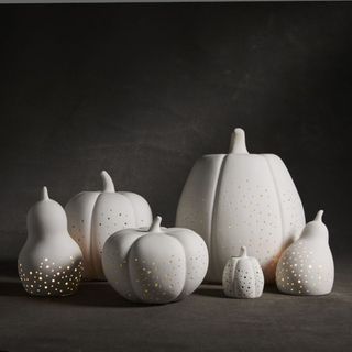 Pierced Porcelain Pumpkins & Gourds against a black background.