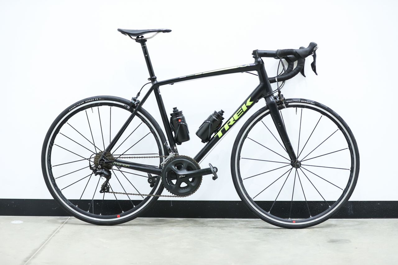 A black and yellow Trek Emonda ALR sits against a white wall