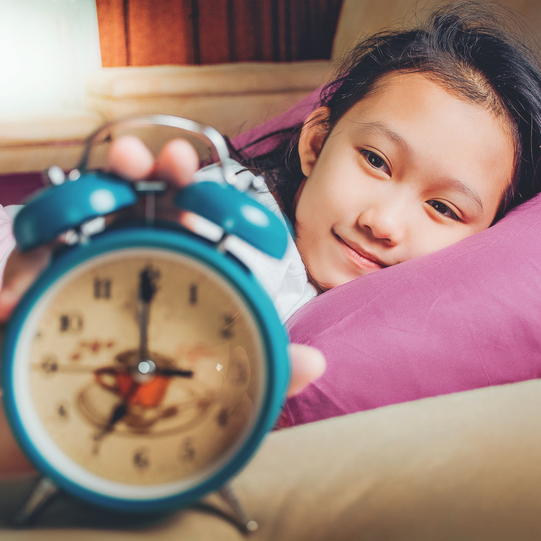 Girl pressing on her alarm clock